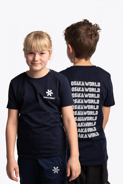 Boy and girl wearing the Osaka kids service games tee short sleeve navy with logo in white. Front and back view