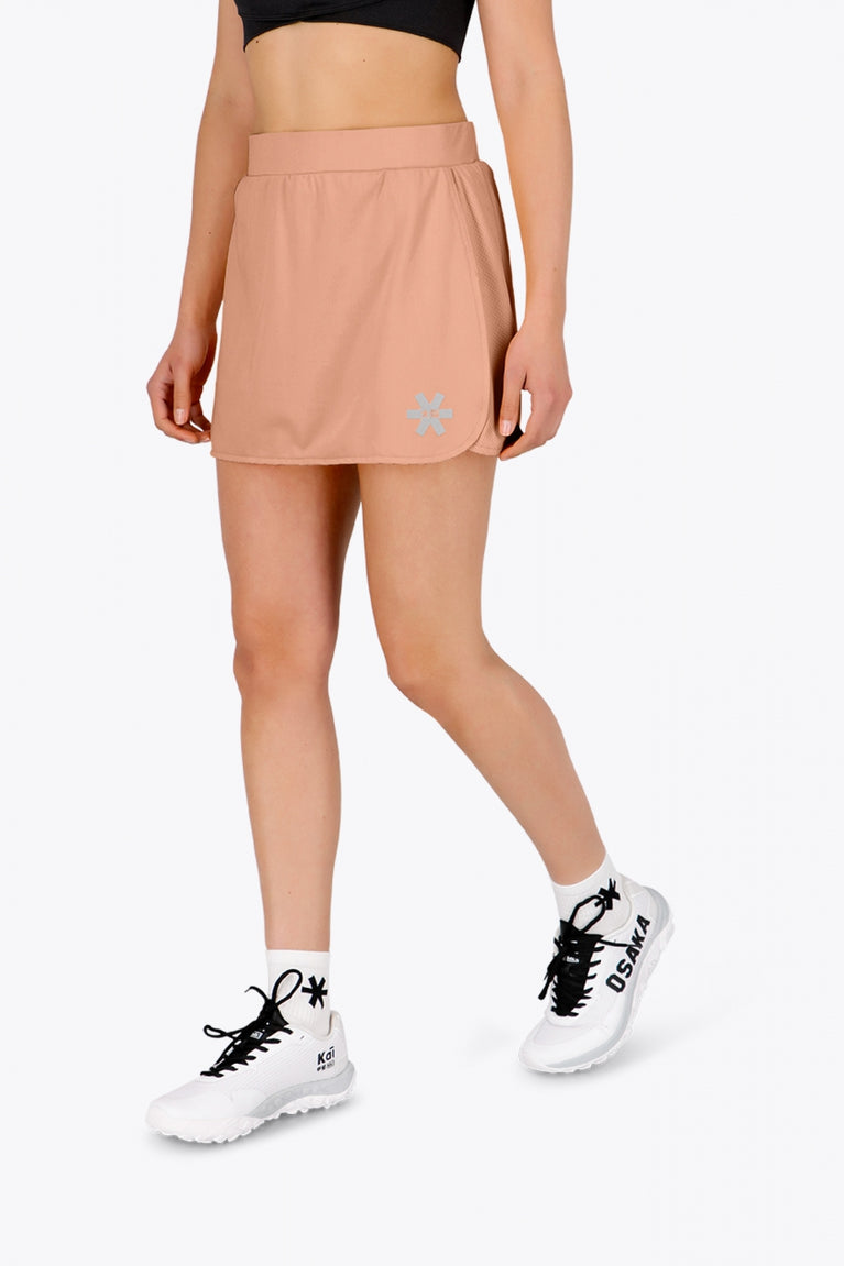 Woman wearing the Osaka women ball skort in peach with logo in grey. Front view