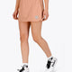 Woman wearing the Osaka women ball skort in peach with logo in grey. Front view