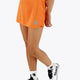 Woman wearing the Osaka women ball skort in orange with logo in white. Front view