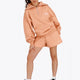 Woman wearing the Osaka women half zip sweater in peach with white logo. Front view