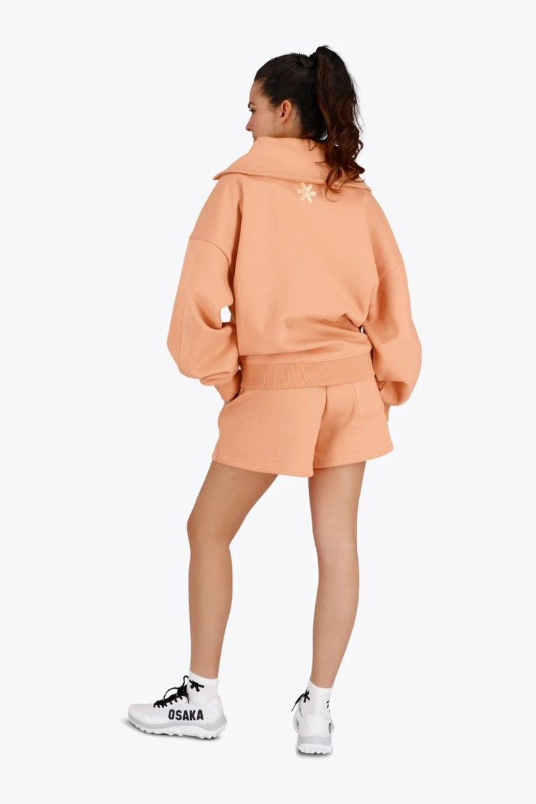 Osaka women half zip sweater in peach with white logo. Back view