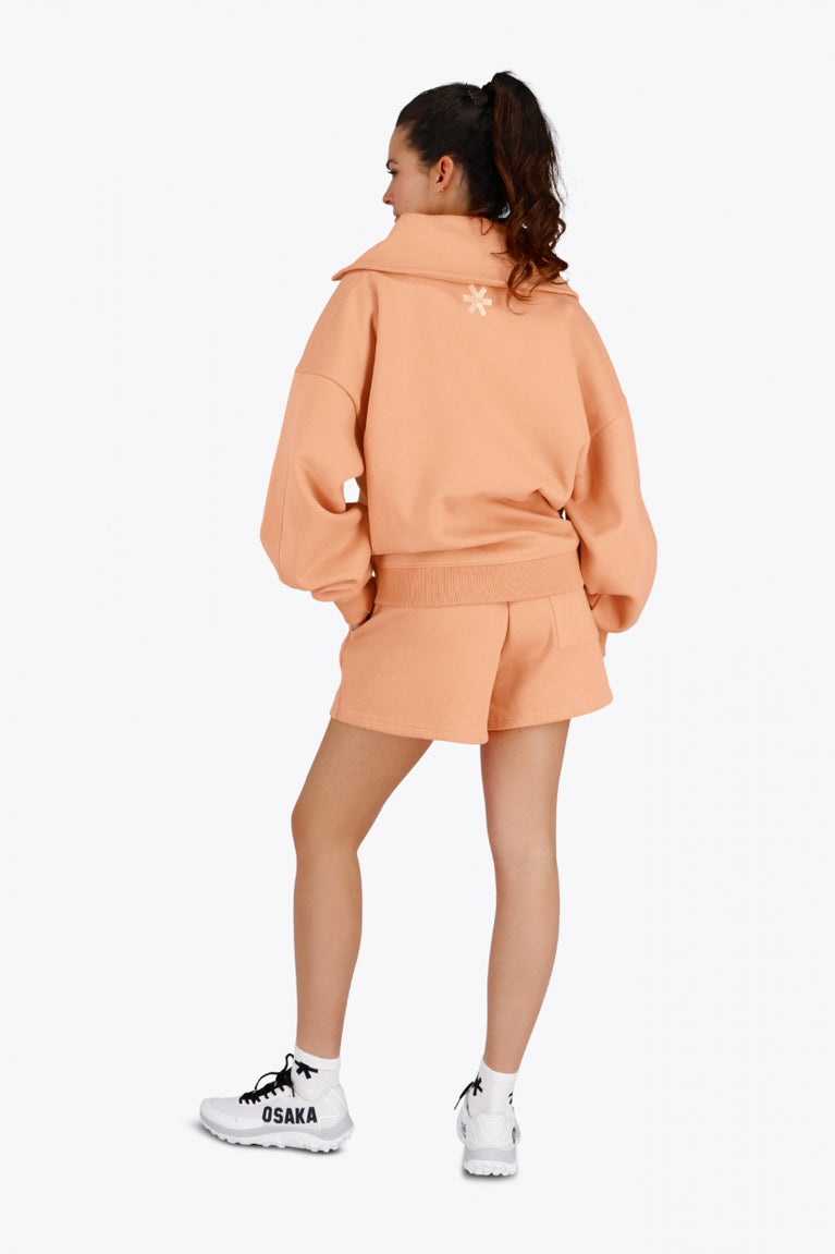 Osaka women half zip sweater in peach with white logo. Back view