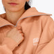 Woman wearing the Osaka women half zip sweater in peach with white logo. Front detail neck view