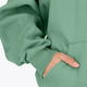 Woman wearing theOsaka women half zip sweater green. Front detail sleeve view