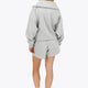 Woman wearing the Osaka women half zip sweater in heather grey with white logo. Back view