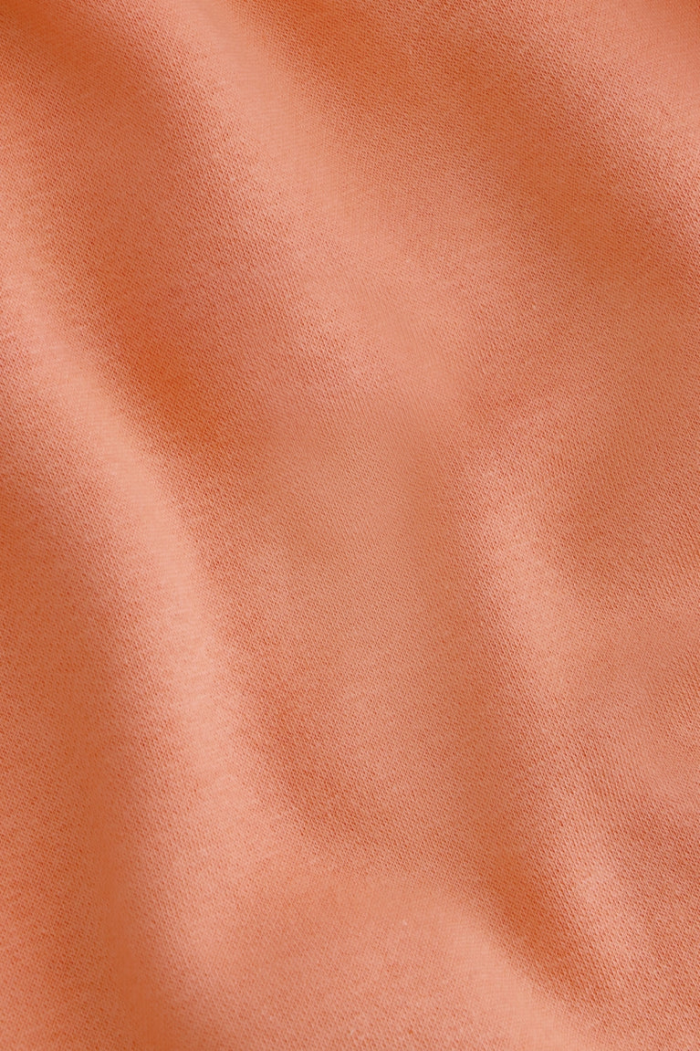 Osaka women hoodie in peach with white logo. Detail fabric view