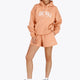 Woman wearing the Osaka women hoodie in peach with white logo. Front view