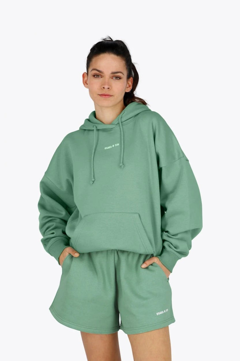 Woman wearing the Osaka women hoodie in green with white logo. Front view