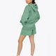 Woman wearing the Osaka women hoodie in green with white logo. Side back view