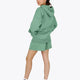 Woman wearing the Osaka women hoodie in green with white logo. Side back view