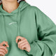 Woman wearing the Osaka women hoodie in green with white logo. Front detail view