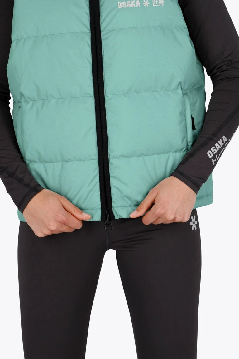 Woman wearing the Osaka women padded gilet in green with grey logo. Front detail view