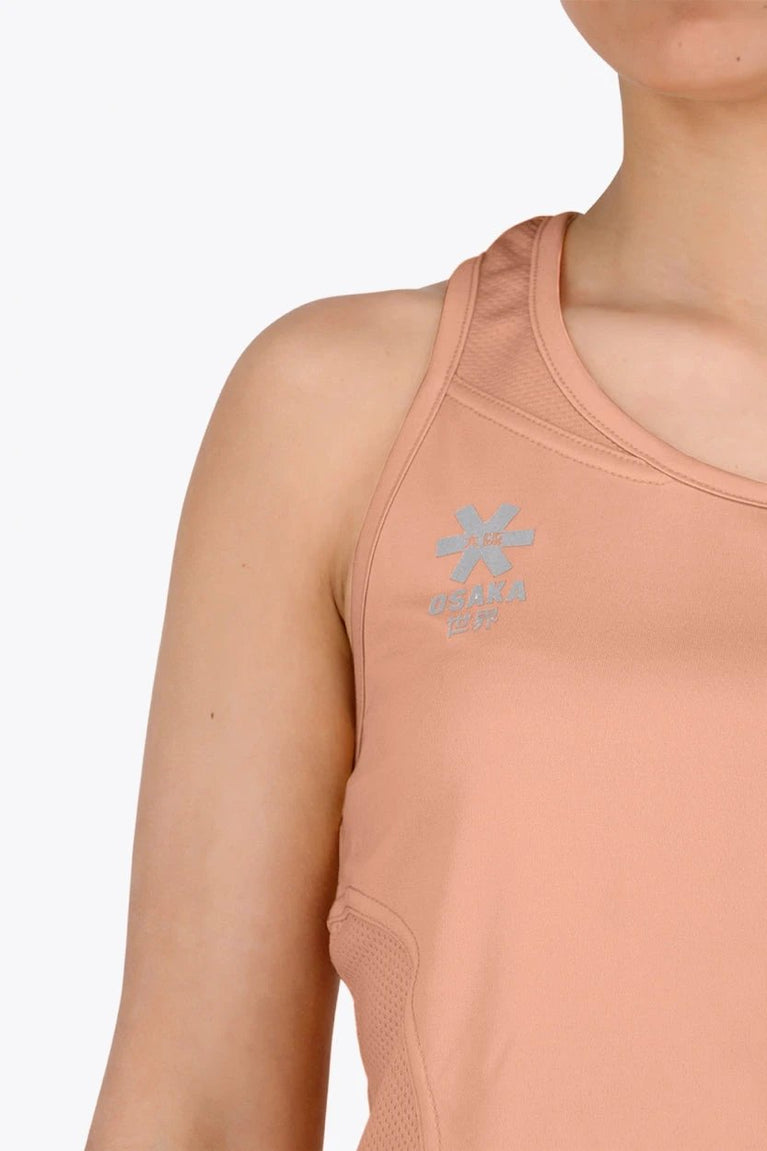 Woman wearing the Osaka women singlet in peach with logo in grey. Front logo view