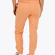 Woman wearing the Osaka women sweatpants in peach with logo in white. Back view