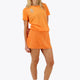 Woman wearing the Osaka women tee short sleeve in orange with logo in grey. Front view