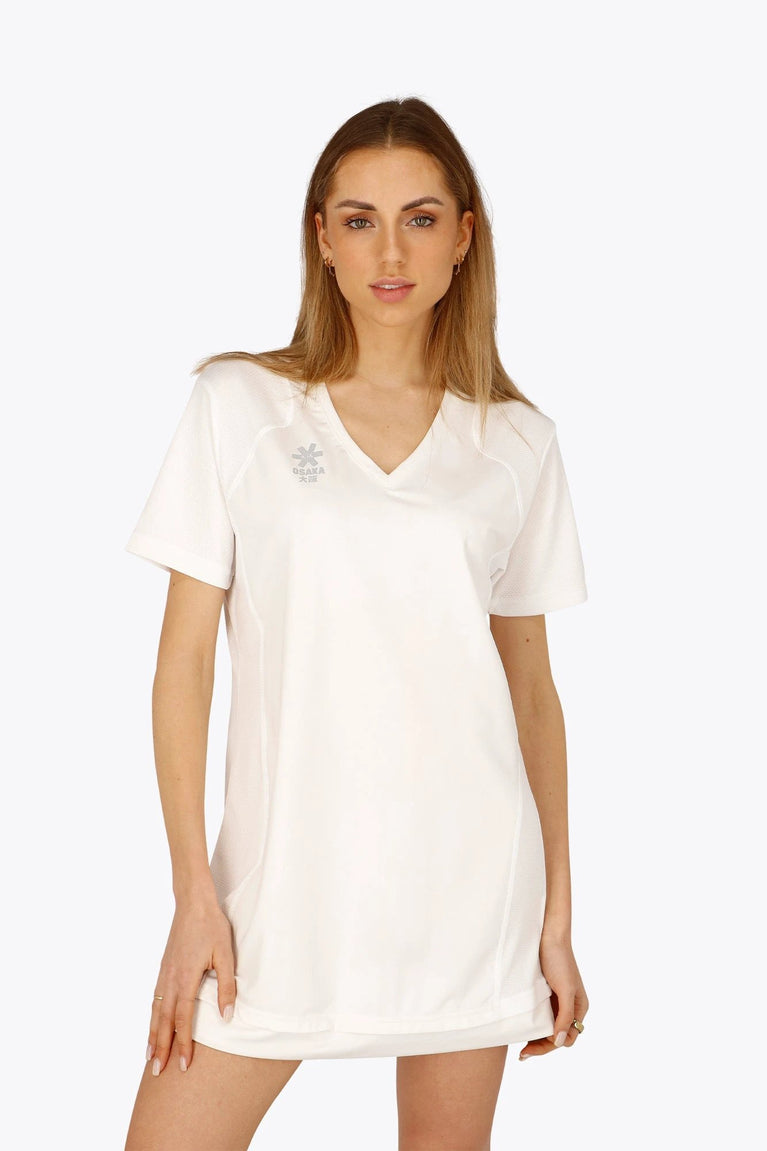 Woman wearing the Osaka women v-neck tech dress in white with logo in grey. Front view