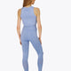 Woman wearing the Osaka women tech tank top in manor blue with logo in grey. Back view