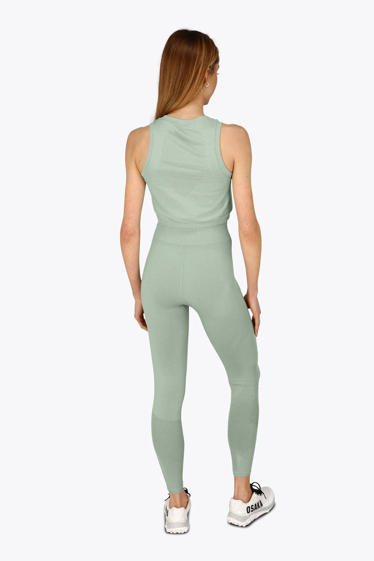 Woman wearing the Osaka women tech tank top in jadeite with logo in grey. Back view