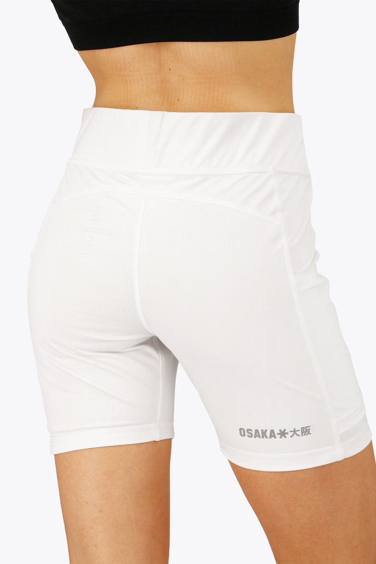 Woman wearing the Osaka women tech short thights in white with grey logo. Back view