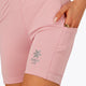 Woman wearing the Osaka women tech short thights in pink with grey logo. Front detail pocket view