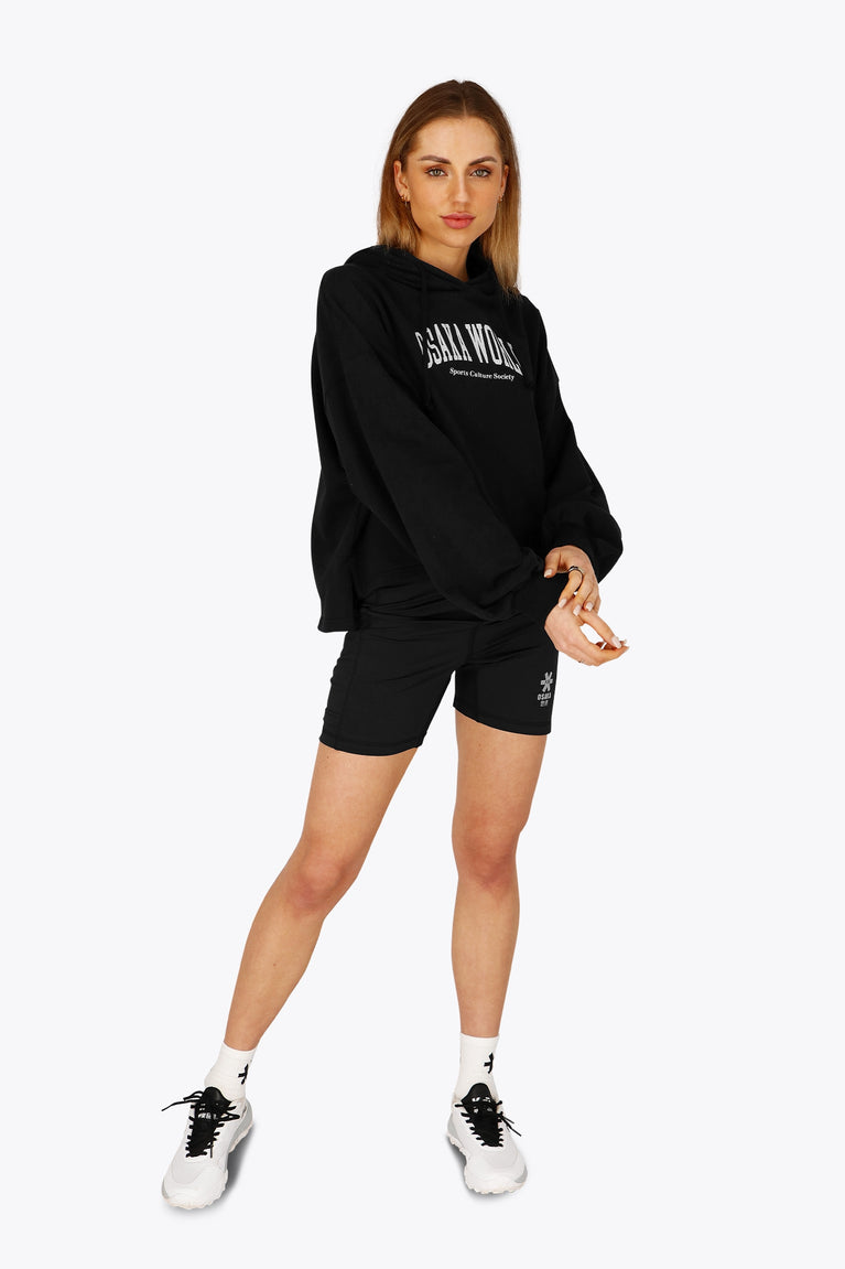 Woman wearing the Osaka women tech short thights in black with grey logo. Front view