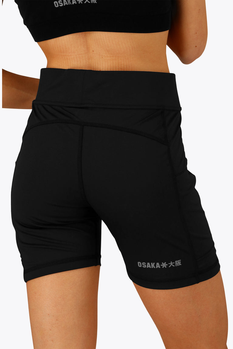 Woman wearing the Osaka women tech short thights in black with grey logo. Back view