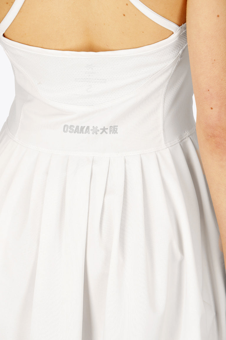 Woman wearing the Osaka women pleated tech dress in white with grey logo. Back detail logo view