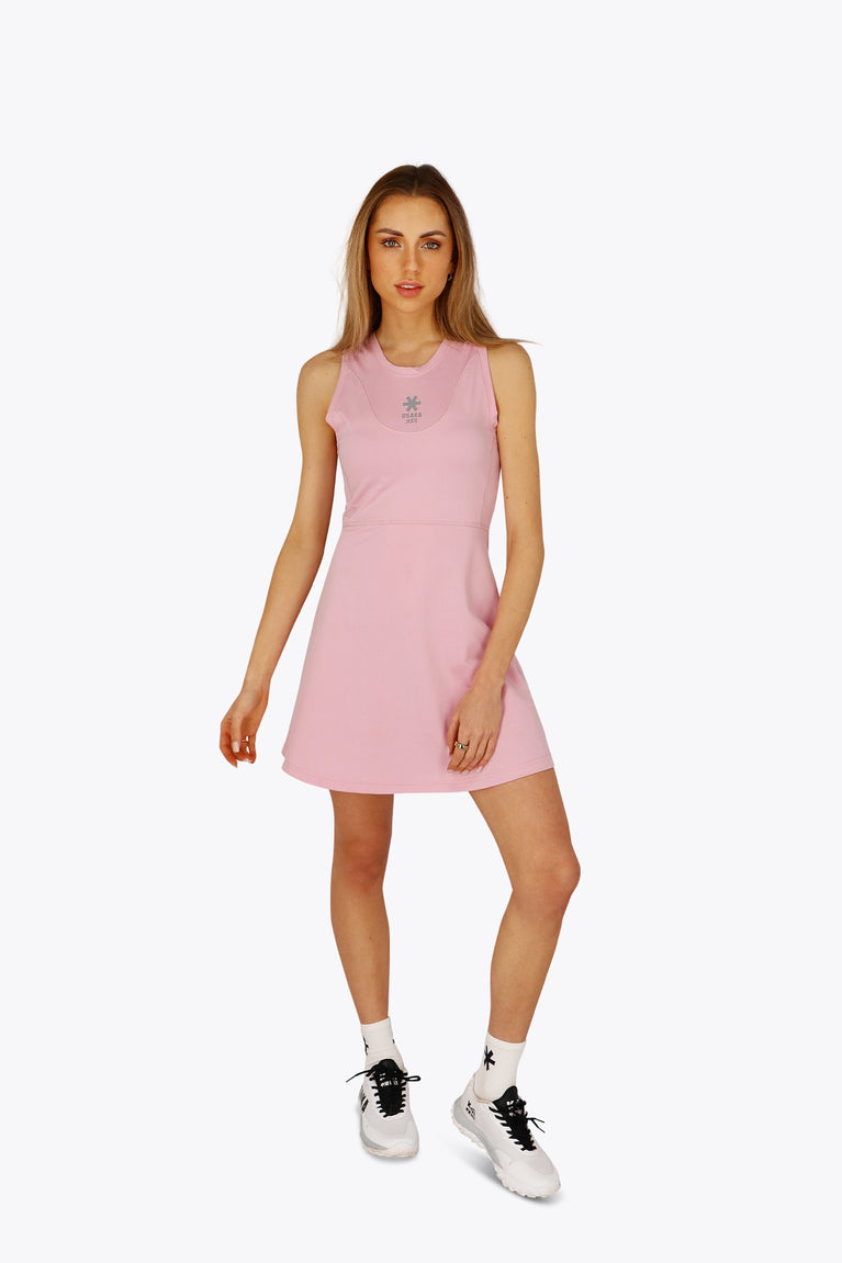 Woman wearing the Osaka women floucy dress pink with logo in grey. Front view