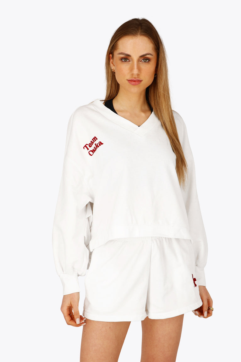 Woman wearing the Osaka women v-neck cropped sweater white with logo in red. Front view