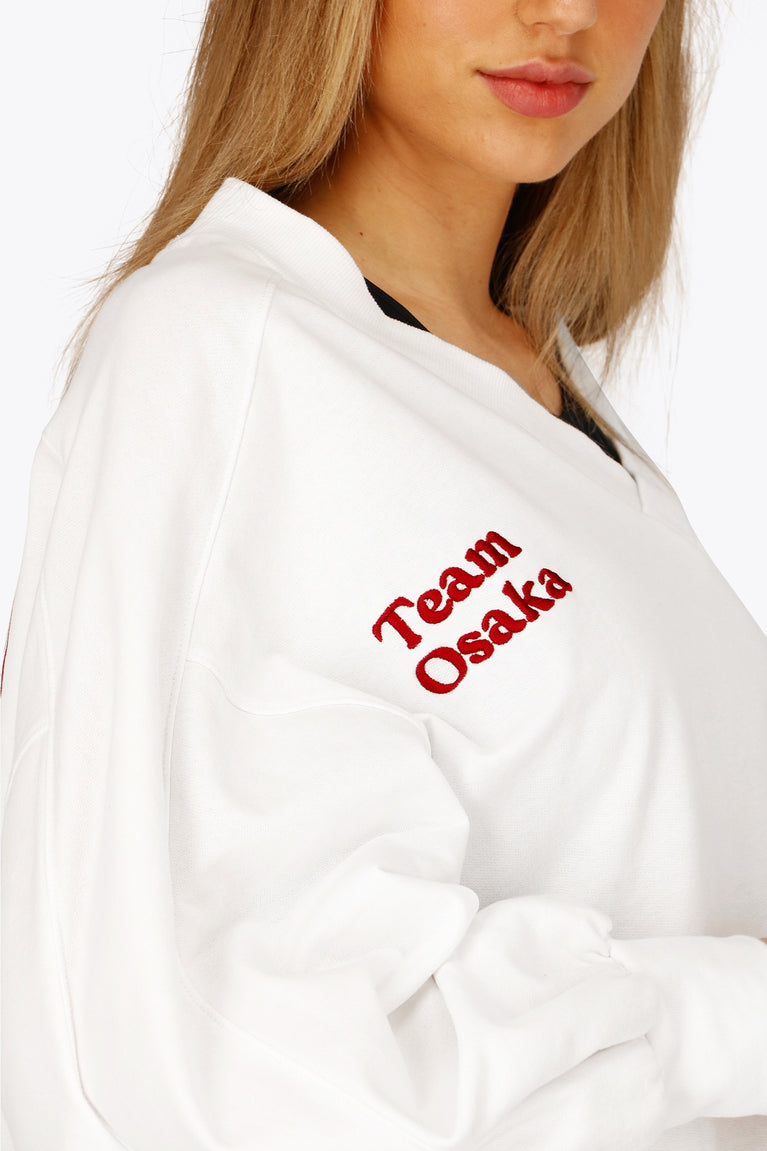 Osaka women v-neck cropped sweater white with logo in red. Front detail logo view