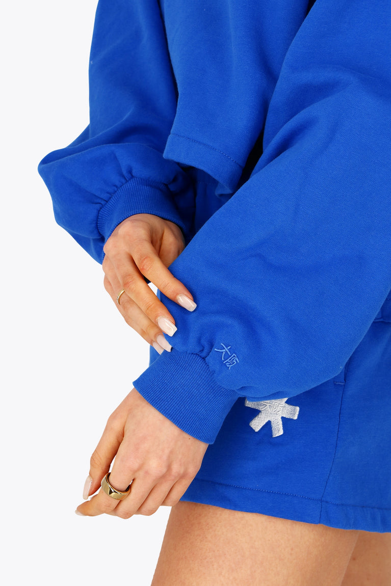 Osaka women cropped hoodie inprincess blue with college logo in white. Front detail sleeve view