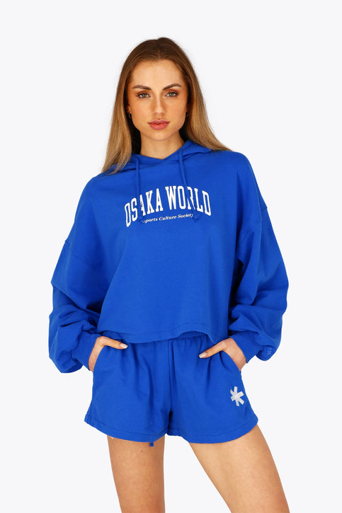 Osaka women cropped hoodie inprincess blue with college logo in white. Front flatlay view