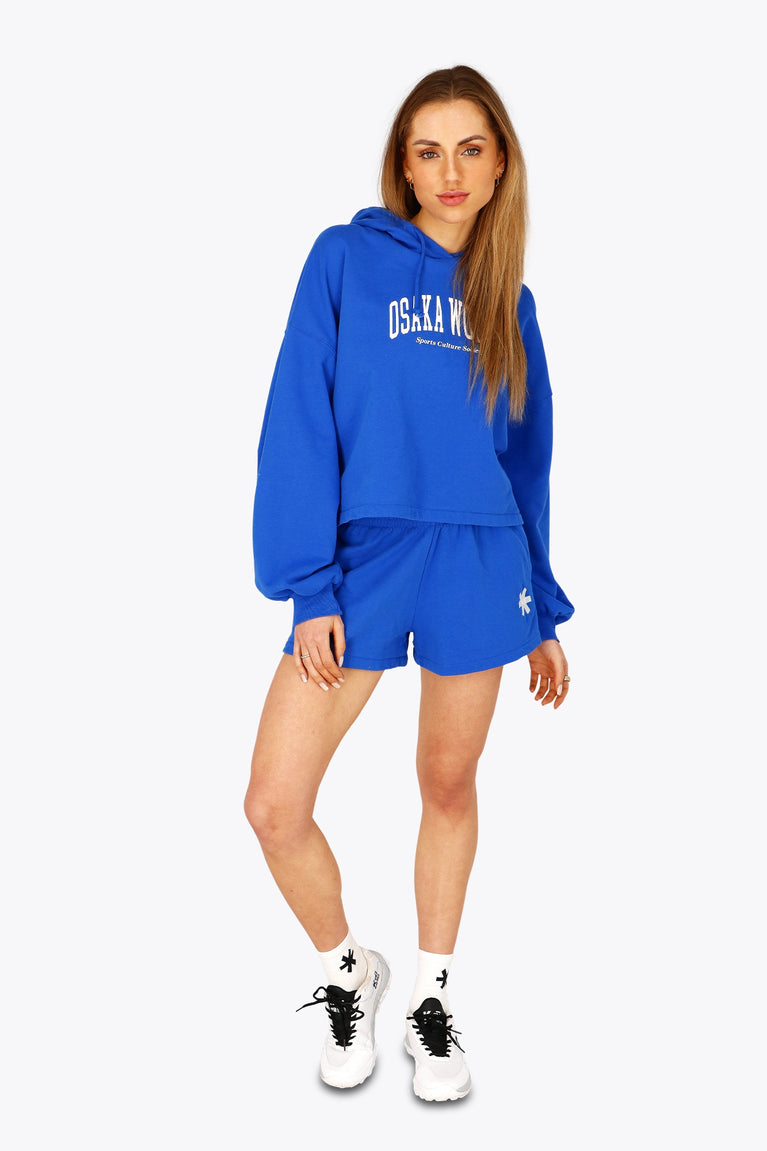 Woman wearing the Osaka women cropped hoodie inprincess blue with college logo in white. Front view