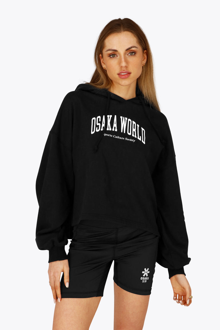 Woman wearing the Osaka women cropped hoodie in black with college logo in white. Front view