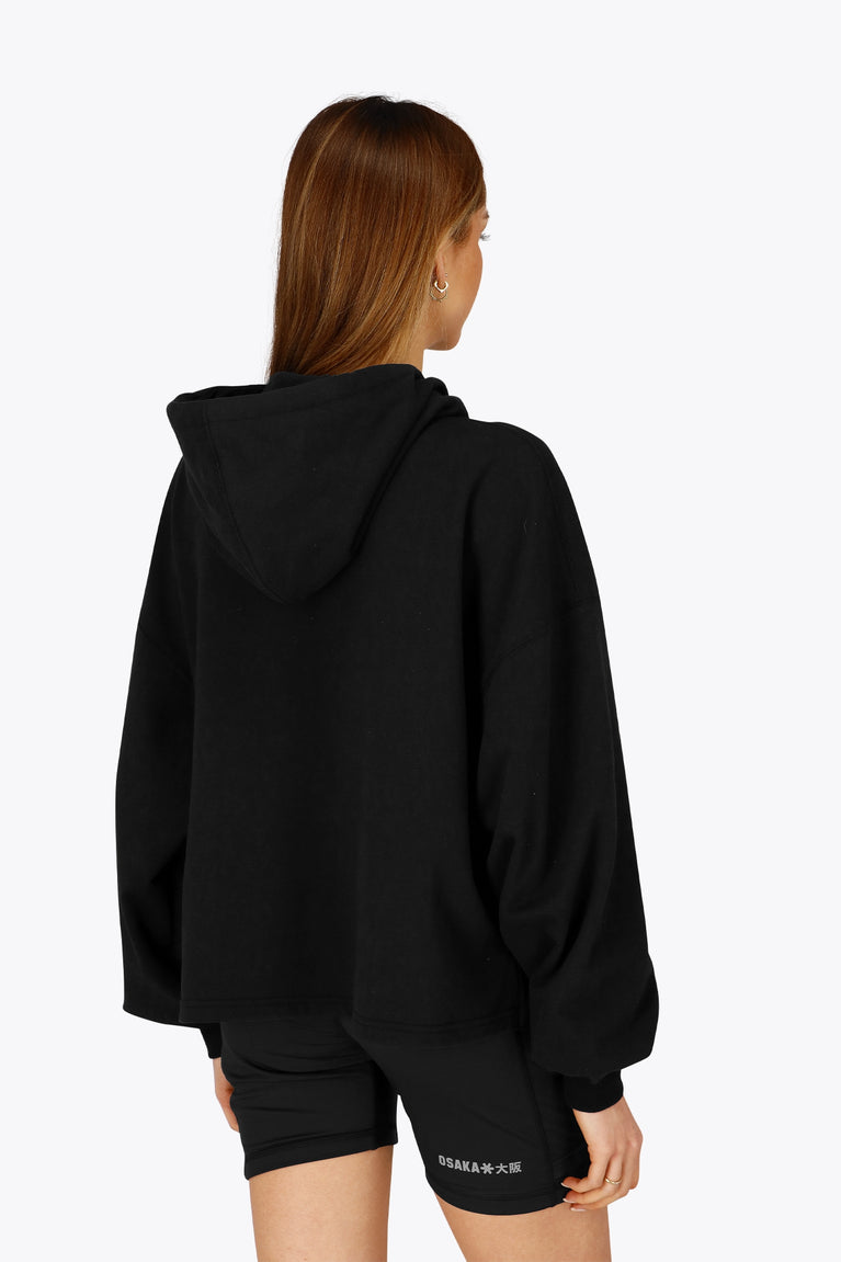 Woman wearing the Osaka women cropped hoodie in black with college logo in white. Back view