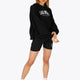 Woman wearing the Osaka women cropped hoodie in black with college logo in white. Front view