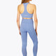 Woman wearing the Osaka women tech sports bra in manor blue with logo in grey. Back view