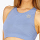 Woman wearing the Osaka women tech sports bra in manor blue with logo in grey. Front detail logo view