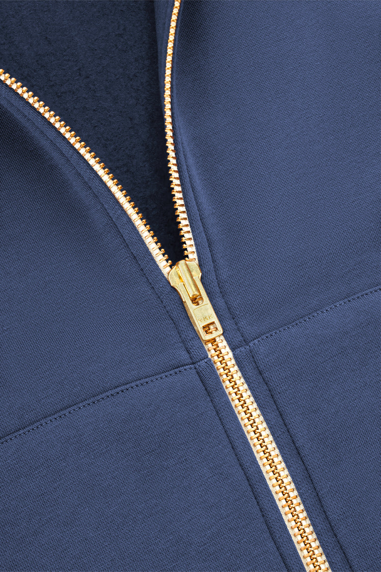 Men's full-zip hoodie zipper close-up, gold-tone tape on dark blue fabric