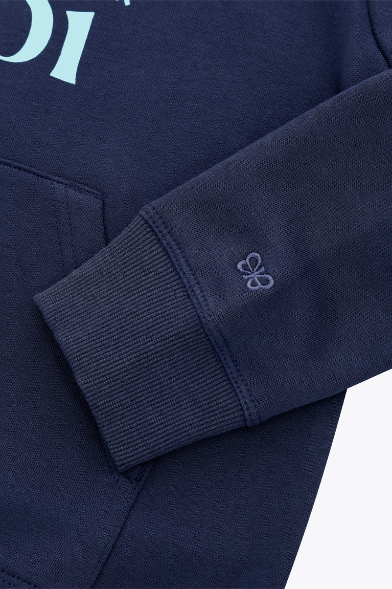Kids deep sea navy hoodie sleeve cuff with small mint flower emblem on cuff.