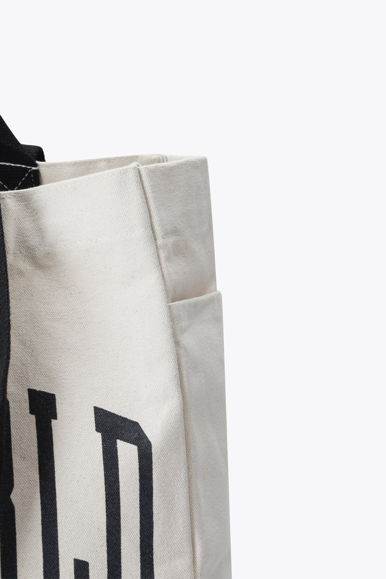 Natural raw tote bag side panel with stitched seam and partial black letter print