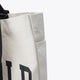 Natural raw tote bag side panel with stitched seam and partial black letter print