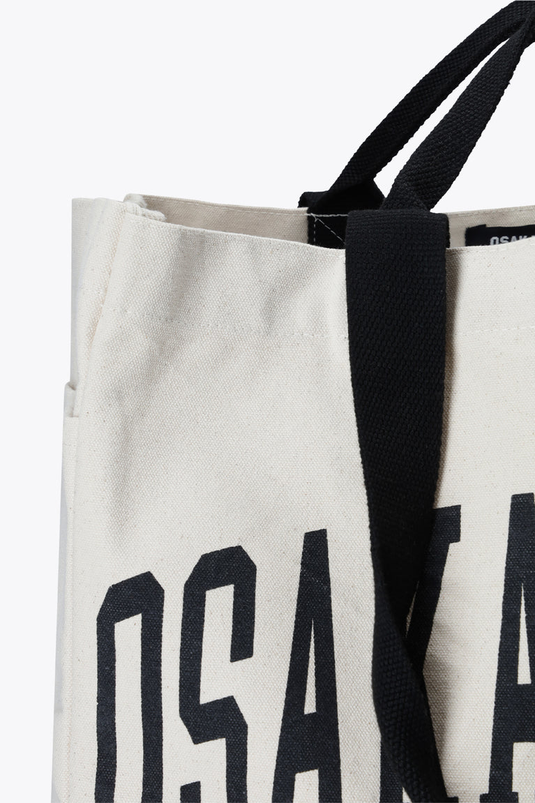 Natural raw tote bag close-up of black handle attachment with partial Osaka World text