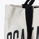 Natural raw tote bag close-up of black handle attachment with partial Osaka World text