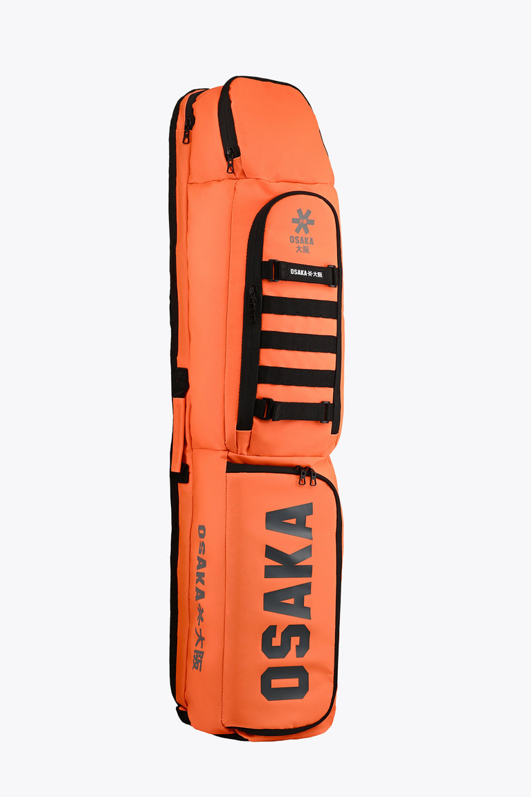 Medium orange stickbag angled view with top carry loop and black pocket panel.