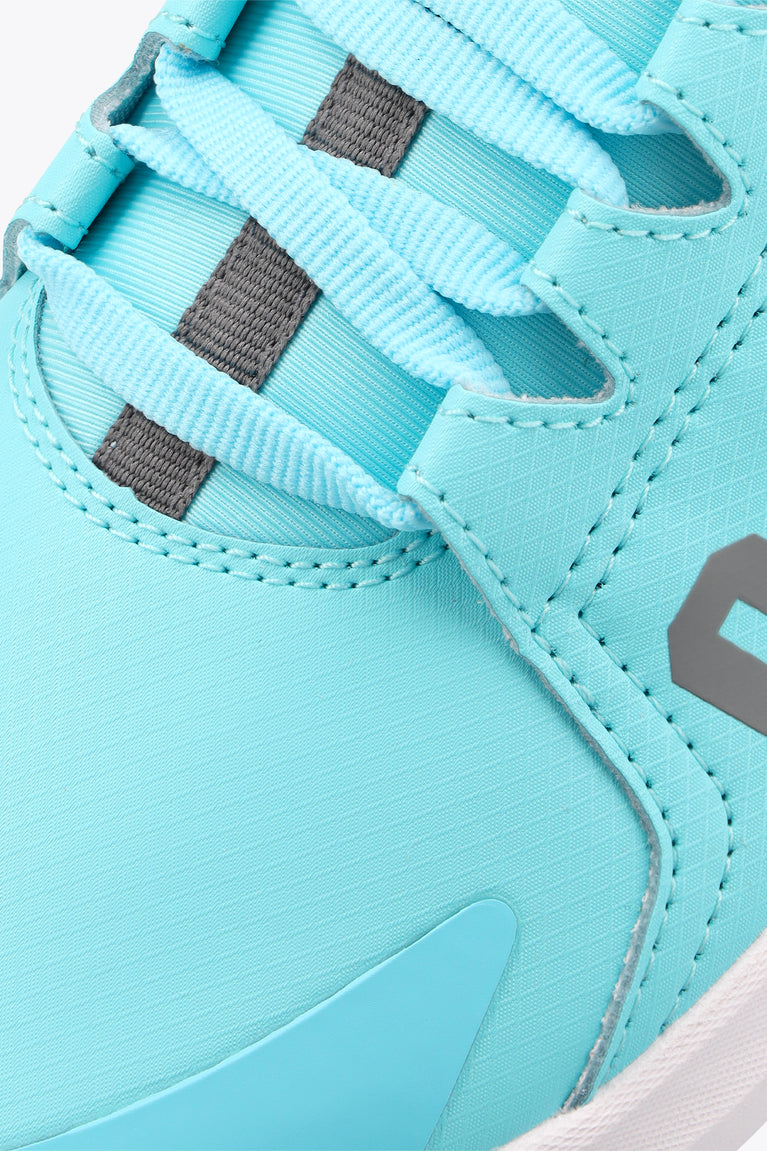 Kids light-blue sneaker side close-up with textured stitching, lace loops, logo patch