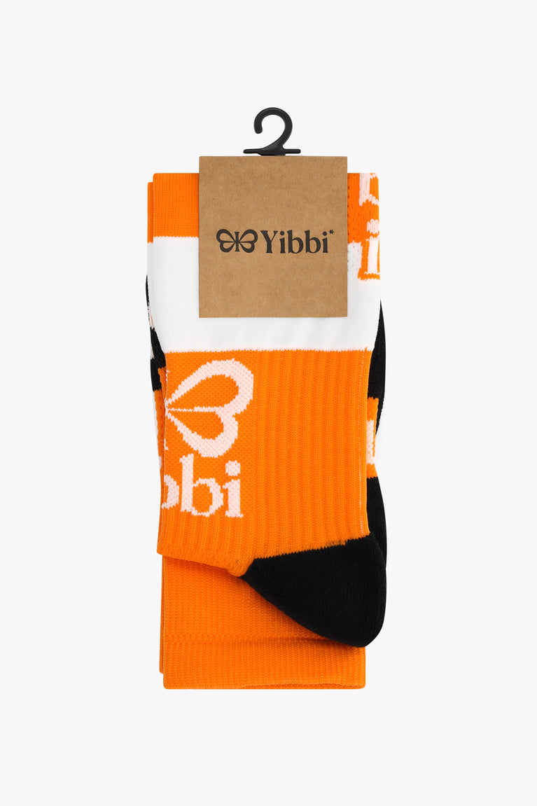 Orange field hockey sock pair in retail box with white and black accents