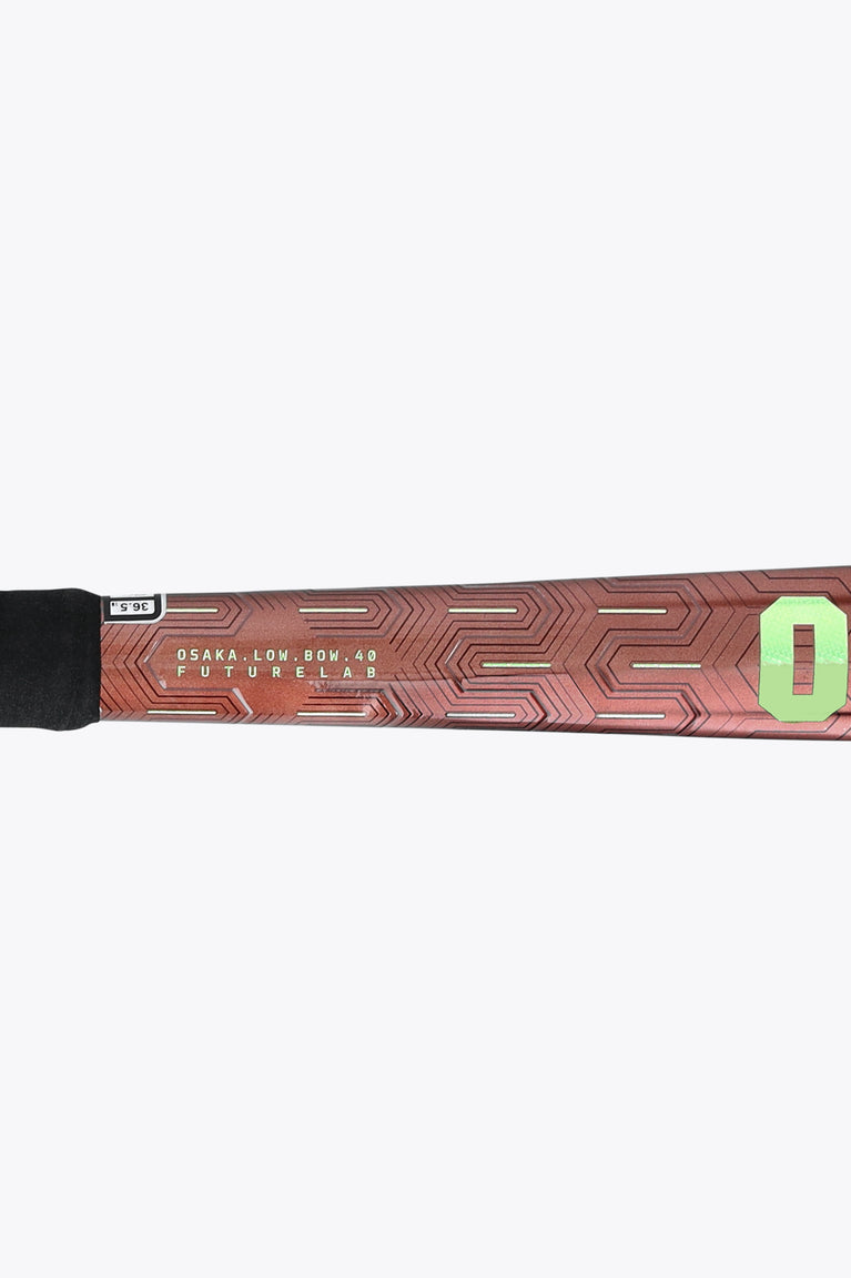 Brown field hockey stick shaft with geometric pattern and green '0' marking near grip.