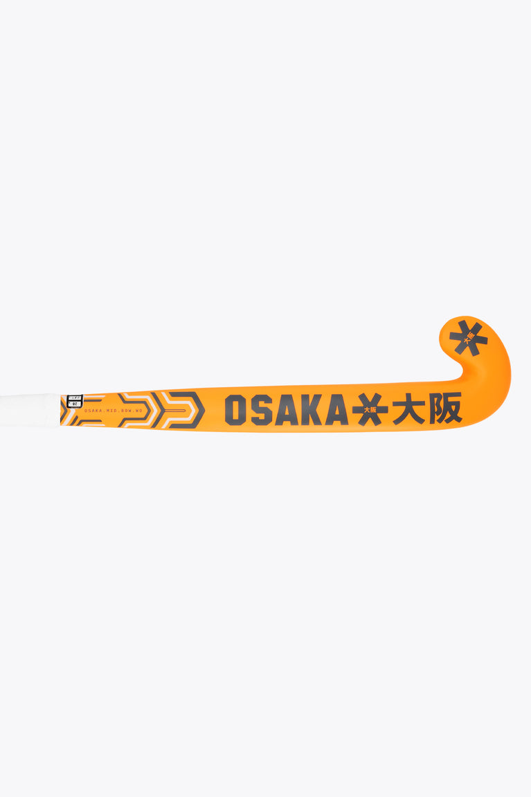 Orange field hockey stick with Osaka lettering and geometric pattern along shaft